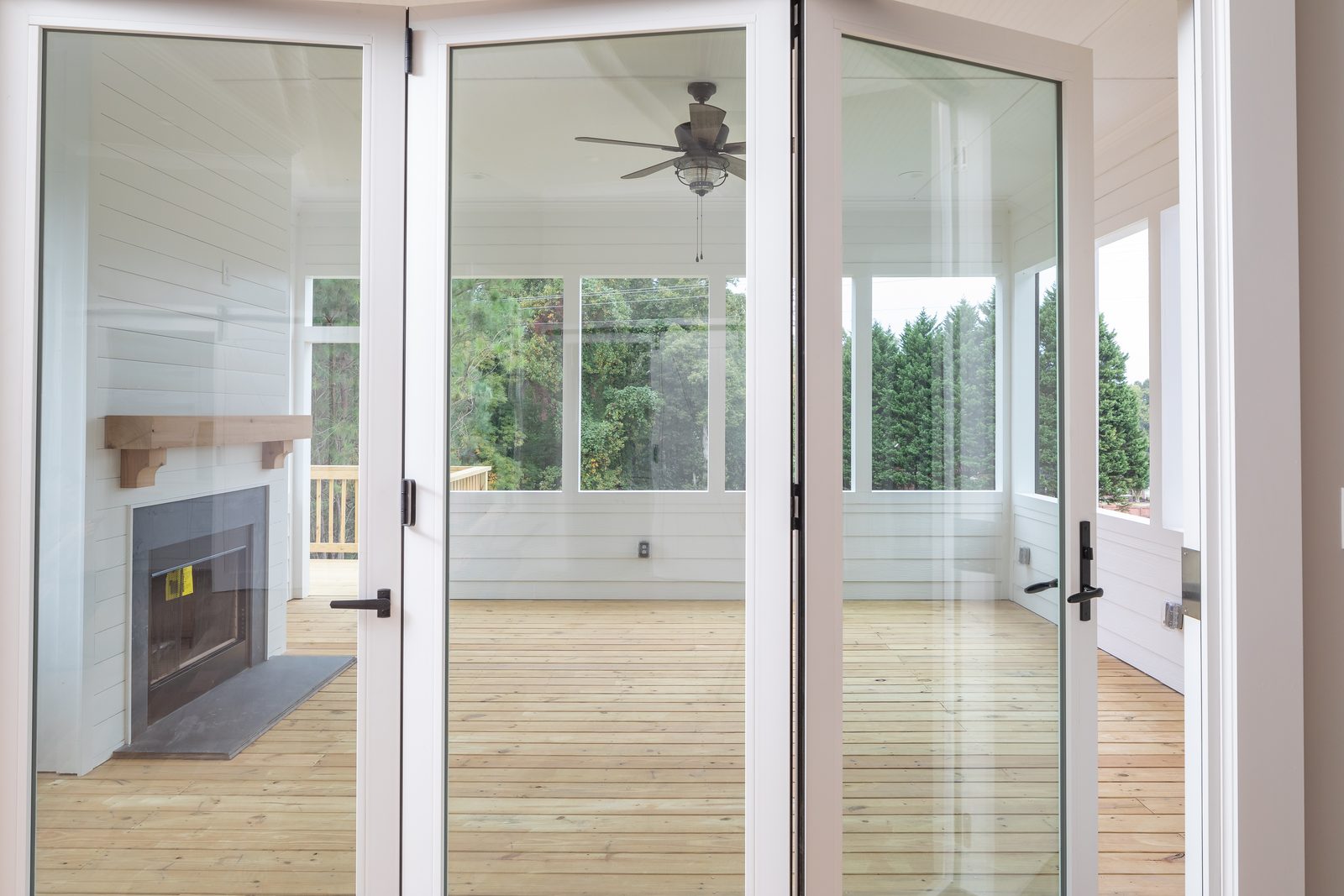 Screened porch with wood-burning fireplace seen through folding glass doors — Shadburn Ferry, custom home built by Ironwood Construction Group in Buford, Georgia