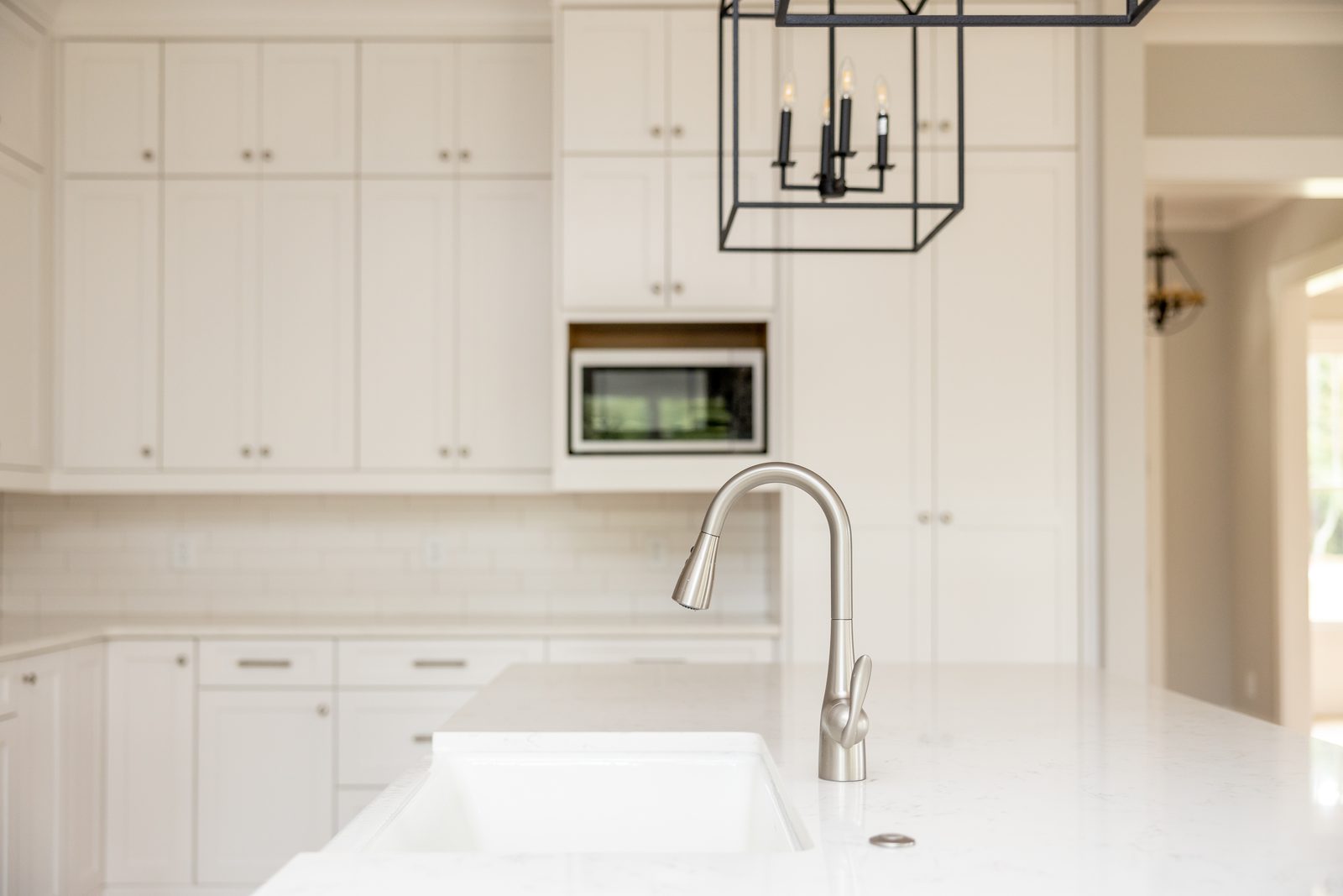 Kitchen sink run with apron-front sink and lantern pendant — Shadburn Ferry, custom home built by Ironwood Construction Group in Buford, Georgia